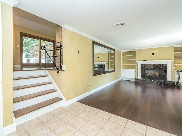 1 Barry Dr, Glen Cove, NY 11542 - unfurnished living room featuring a fireplace, built in shelves, wood finished floors, stairway, and crown molding