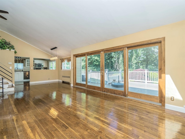 1 Barry Dr, Glen Cove, NY 11542 - unfurnished living room featuring wood finished floors, radiator, stairway, a ceiling fan, and vaulted ceiling