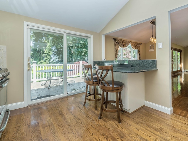 1 Barry Dr, Glen Cove, NY 11542 - kitchen featuring lofted ceiling, wood finished floors, a kitchen bar, and range
