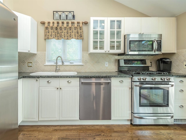 1 Barry Dr, Glen Cove, NY 11542 - kitchen featuring appliances with stainless steel finishes, dark countertops, lofted ceiling, and glass insert cabinets