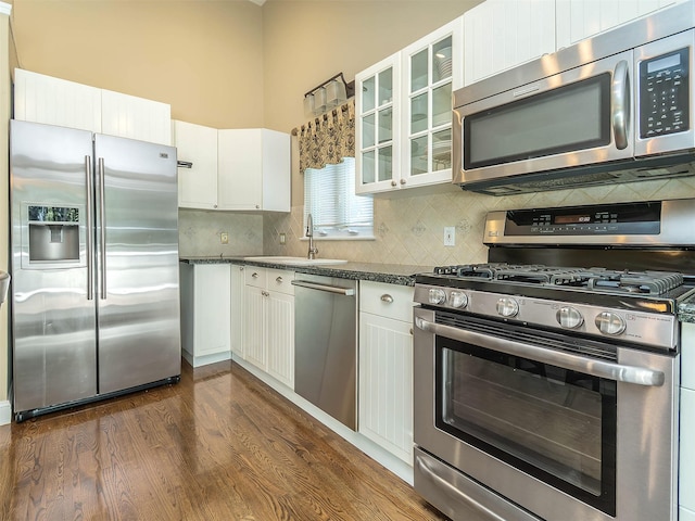 1 Barry Dr, Glen Cove, NY 11542 - kitchen featuring stainless steel appliances, white cabinets, decorative backsplash, dark wood-style floors, and dark countertops