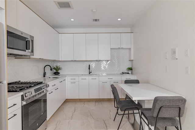 17 Union Rd Unit 108, Spring Valley, NY 10977 - kitchen with stainless steel appliances, light marble finish flooring, light countertops, white cabinetry, and tasteful backsplash