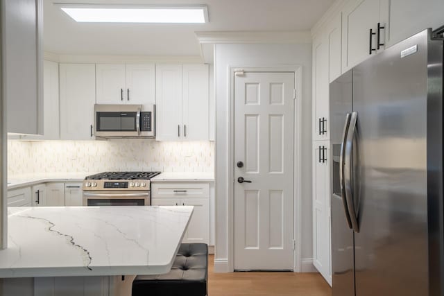 67-23 182nd St, Fresh Meadows, NY 11365 - kitchen featuring appliances with stainless steel finishes, decorative backsplash, light stone counters, and light wood-style flooring