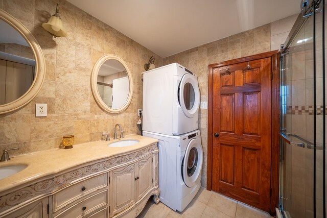 67-23 182nd St, Fresh Meadows, NY 11365 - laundry area featuring stacked washing machine and dryer, light tile patterned floors, and tile walls