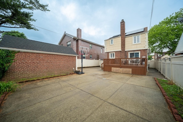 67-23 182nd St, Fresh Meadows, NY 11365 - rear view of property featuring brick siding, a patio area, a fenced backyard, solar panels, and a deck