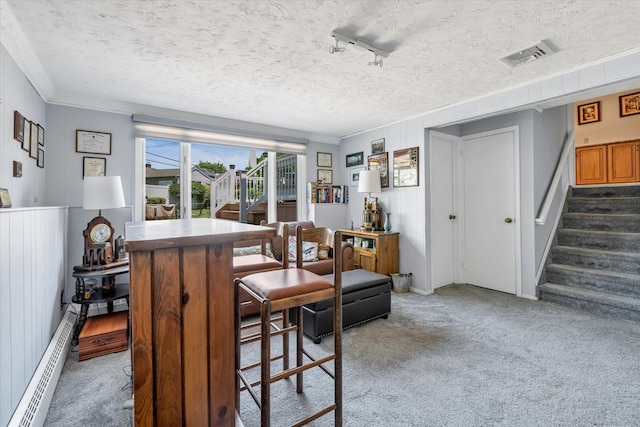 1182 Adrienne Ln, Seaford, NY 11783 - dining space featuring dark colored carpet, stairway, a baseboard radiator, a textured ceiling, and crown molding