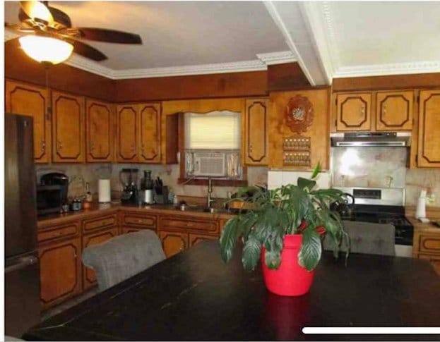 135-15 243rd St, Rosedale, NY 11422 - kitchen featuring stainless steel range oven, brown cabinets, a ceiling fan, freestanding refrigerator, and under cabinet range hood