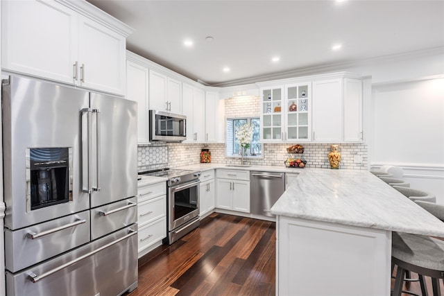114 Atlantic Ave Unit 82, Lynbrook, NY 11563 - kitchen featuring appliances with stainless steel finishes, a peninsula, a breakfast bar, white cabinets, and decorative backsplash