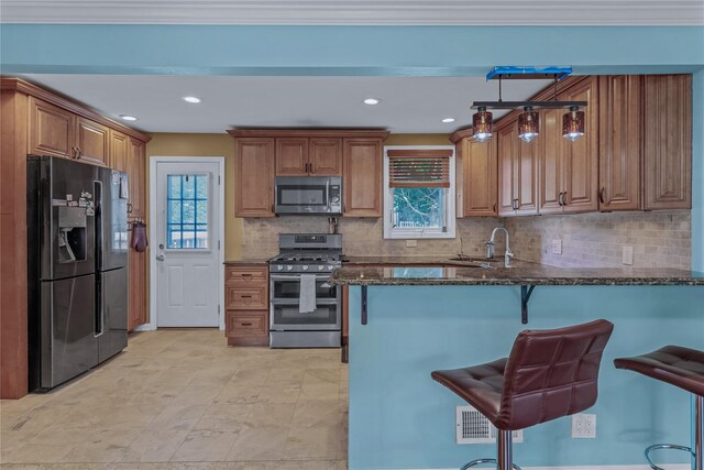 72 Harris Ave, Hewlett, NY 11557 - kitchen featuring stainless steel appliances, dark stone counters, brown cabinetry, a peninsula, and a breakfast bar area