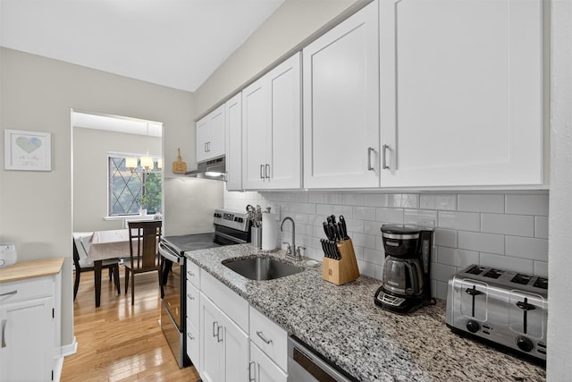 129 Main St Unit D12, Cornwall, NY 12518 - kitchen with appliances with stainless steel finishes, under cabinet range hood, white cabinets, light stone countertops, and backsplash
