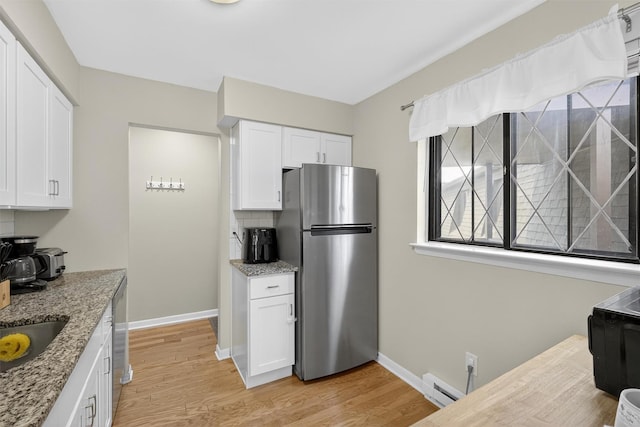 129 Main St Unit D12, Cornwall, NY 12518 - kitchen with freestanding refrigerator, a baseboard heating unit, white cabinetry, and light stone countertops