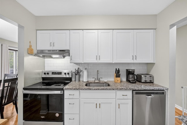 129 Main St Unit D12, Cornwall, NY 12518 - kitchen featuring stainless steel appliances, exhaust hood, light stone counters, white cabinets, and backsplash