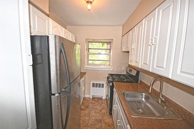 221 Middle Neck Rd Unit I-3, Great Neck, NY 11021 - kitchen featuring appliances with stainless steel finishes, radiator, dark countertops, and white cabinetry