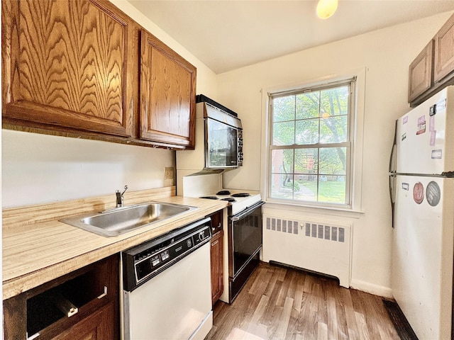 182 Pinewood Rd Unit 28, Hartsdale, NY 10530 - kitchen featuring white appliances, radiator heating unit, light wood-style flooring, and light countertops