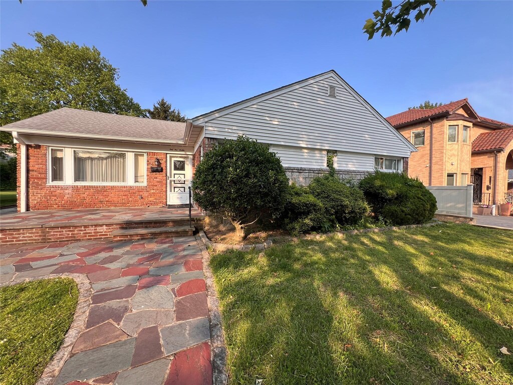 64-19 Marathon Pkwy, Little Neck, NY 11362 - view of front facade featuring brick siding and a front lawn