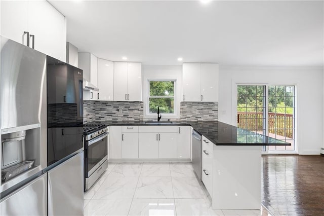 52 Broadway, Piermont, NY 10968 - kitchen with stainless steel appliances, a peninsula, white cabinetry, under cabinet range hood, and crown molding