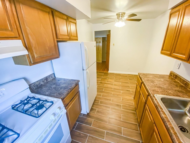 1365 Crosby Ave, Bronx, NY 10461 - kitchen with white appliances, under cabinet range hood, brown cabinetry, and wood finish floors