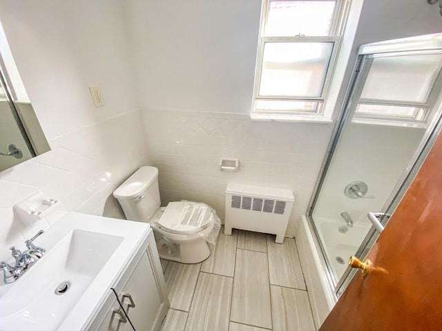1365 Crosby Ave, Bronx, NY 10461 - full bathroom featuring radiator heating unit, tile walls, vanity, combined bath / shower with glass door, and a wainscoted wall