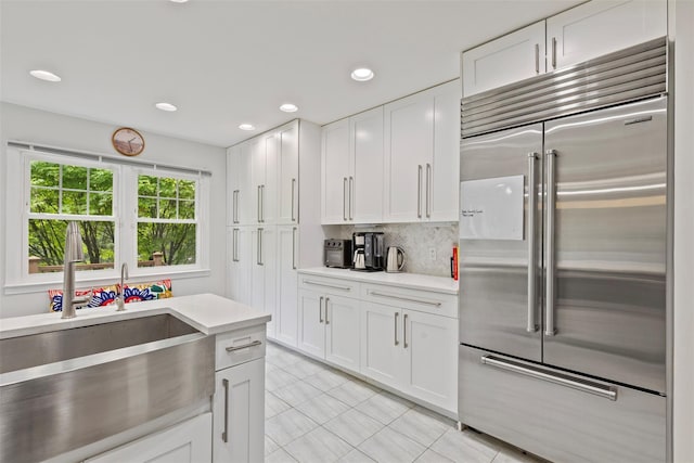 8 Sylvan Ln, Scarsdale, NY 10583 - kitchen with stainless steel built in fridge, light countertops, decorative backsplash, light tile patterned floors, and white cabinetry