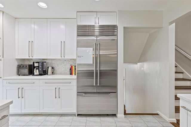 8 Sylvan Ln, Scarsdale, NY 10583 - kitchen with built in refrigerator, light countertops, white cabinetry, tasteful backsplash, and light tile patterned floors