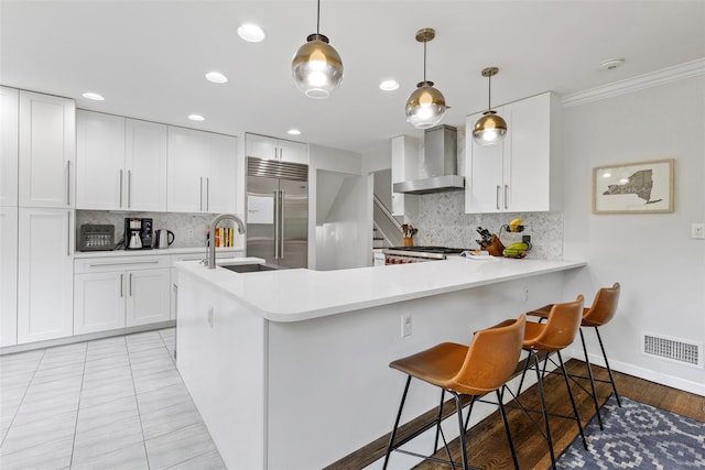 8 Sylvan Ln, Scarsdale, NY 10583 - kitchen with built in refrigerator, wall chimney range hood, decorative backsplash, light countertops, and recessed lighting