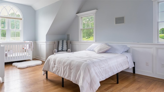 55 Charm City Dr, Port Jefferson Station, NY 11776 - bedroom with vaulted ceiling, wood finished floors, a decorative wall, and a wainscoted wall