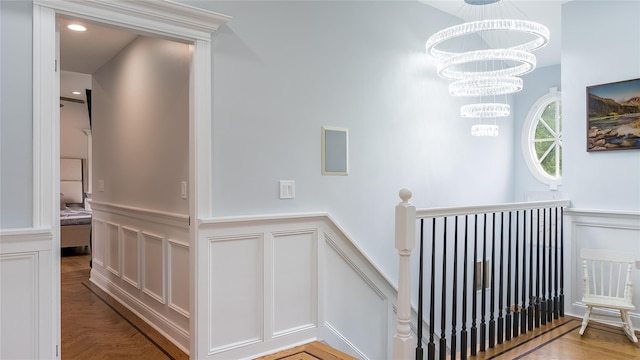 55 Charm City Dr, Port Jefferson Station, NY 11776 - stairway with a decorative wall, a wainscoted wall, and a chandelier