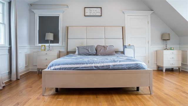 55 Charm City Dr, Port Jefferson Station, NY 11776 - bedroom featuring light wood-style floors, vaulted ceiling, a wainscoted wall, a decorative wall, and multiple windows