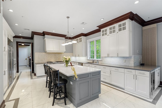 3747 Purchase St, Purchase, NY 10577 - kitchen with ornamental molding, light marble finish floors, a breakfast bar, custom range hood, and a kitchen island