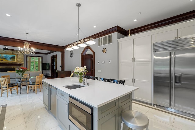 3747 Purchase St, Purchase, NY 10577 - kitchen with built in appliances, ornamental molding, a kitchen island with sink, light countertops, and decorative light fixtures