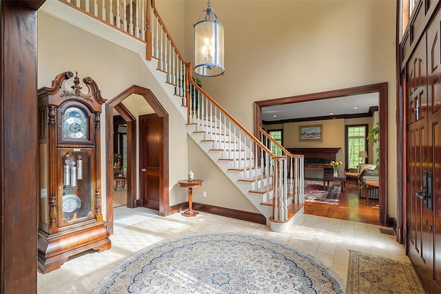 3747 Purchase St, Purchase, NY 10577 - tiled entrance foyer featuring a high ceiling, stairway, a fireplace, arched walkways, and crown molding
