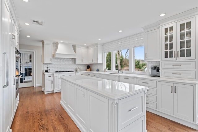 8 Pippin Ln, Lloyd Harbor, NY 11743 - kitchen featuring premium range hood, gas cooktop, tasteful backsplash, white cabinets, and light wood-style floors