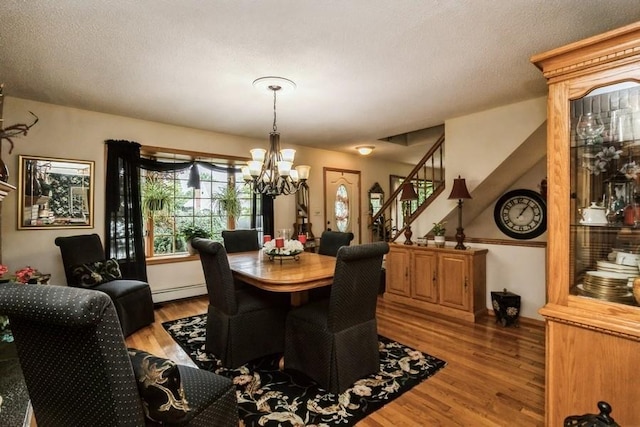 2209 Post St, East Meadow, NY 11554 - dining area featuring a chandelier, wood finished floors, stairway, a baseboard radiator, and a textured ceiling