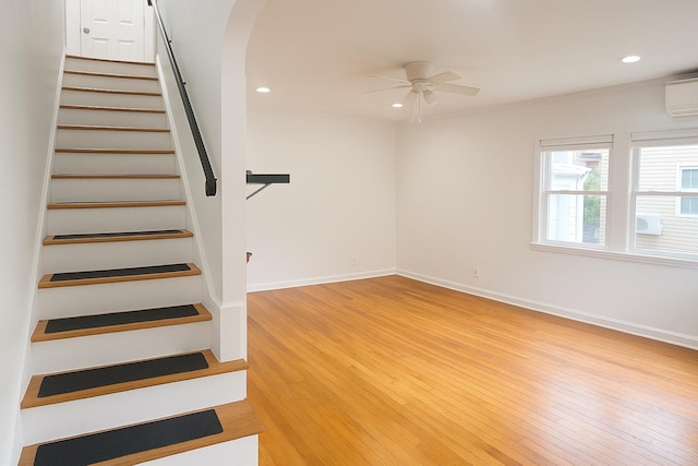 26 Sherman Rd, Farmingdale, NY 11735 - staircase with arched walkways, wood finished floors, a ceiling fan, a wall unit AC, and recessed lighting