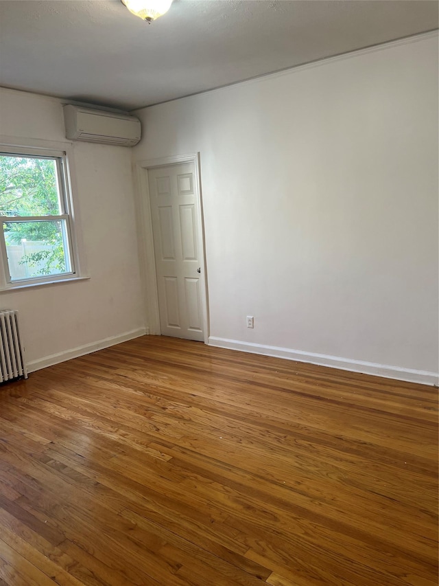 26 Sherman Rd, Farmingdale, NY 11735 - empty room featuring a wall mounted AC, radiator, and wood finished floors
