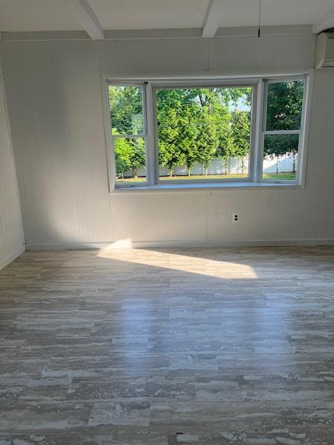 26 Sherman Rd, Farmingdale, NY 11735 - spare room with wood finished floors, an AC wall unit, and beam ceiling