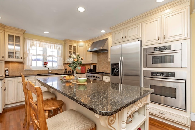 1277 Jerusalem Ave, Merrick, NY 11566 - kitchen featuring wall chimney exhaust hood, stainless steel appliances, cream cabinets, wood finished floors, and recessed lighting