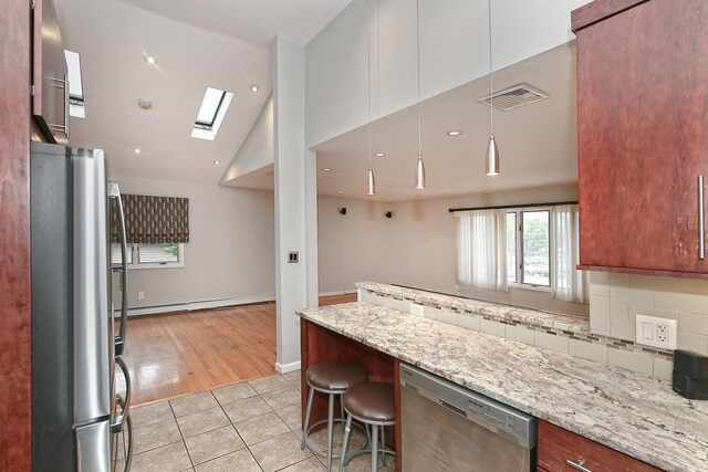 36 Dawes Ave, Syosset, NY 11791 - kitchen with stainless steel appliances, a baseboard heating unit, light tile patterned flooring, light stone countertops, and lofted ceiling