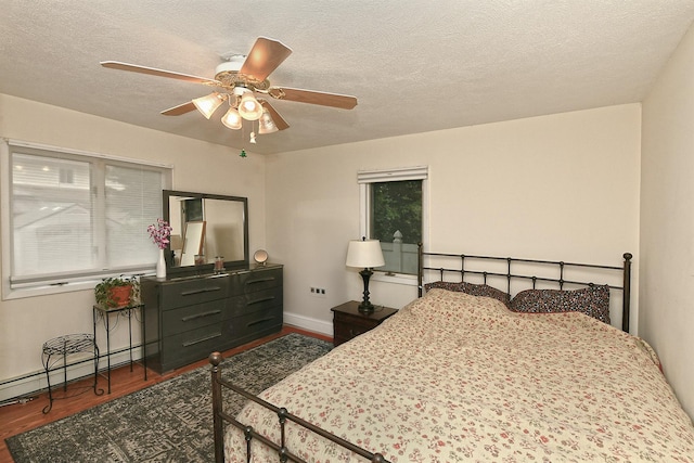 36 Dawes Ave, Syosset, NY 11791 - bedroom featuring wood finished floors, a baseboard radiator, a textured ceiling, and ceiling fan