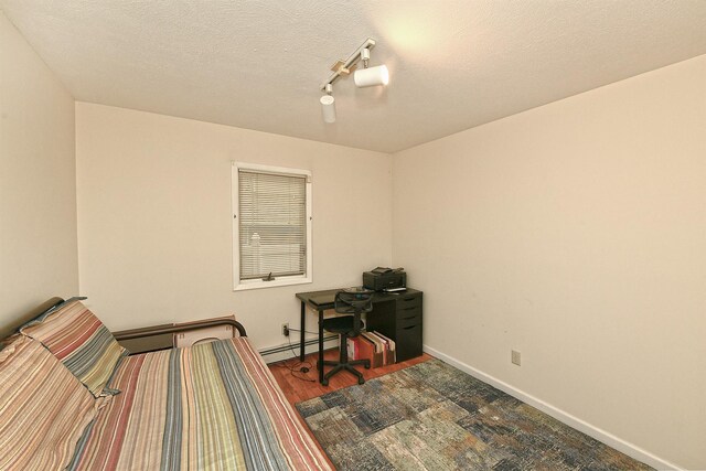 36 Dawes Ave, Syosset, NY 11791 - bedroom with baseboard heating, wood finished floors, a textured ceiling, and rail lighting