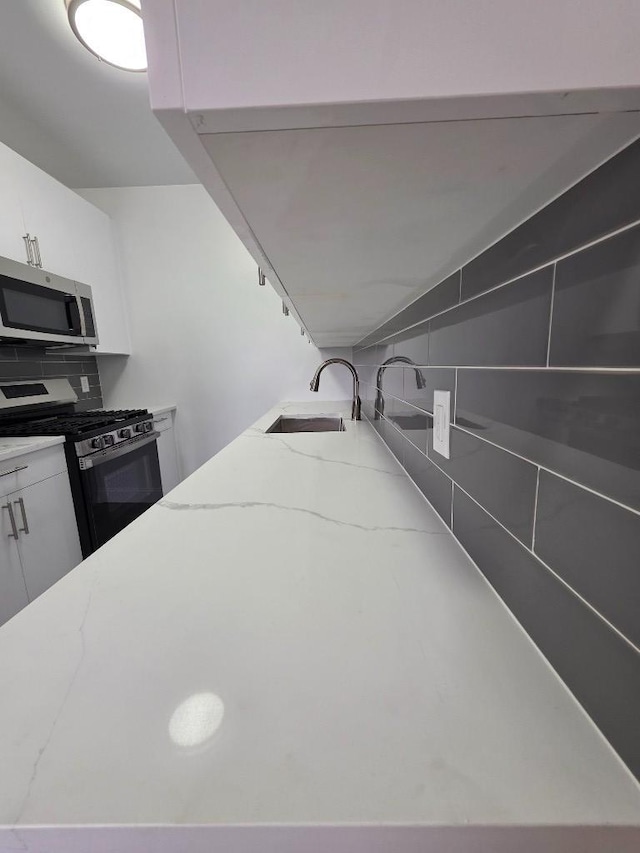 43-42 45th St Unit 4O, Sunnyside, NY 11104 - kitchen with appliances with stainless steel finishes, light stone counters, and white cabinetry