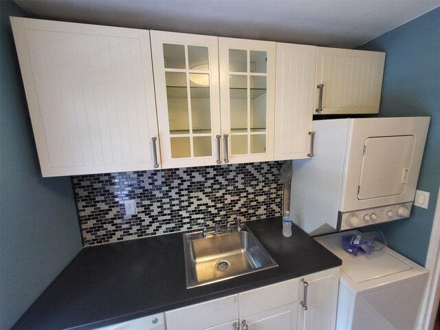 224-23 Kingsbury Ave Unit B, Oakland Gardens, NY 11364 - kitchen featuring dark countertops, stacked washer and clothes dryer, decorative backsplash, and white cabinets