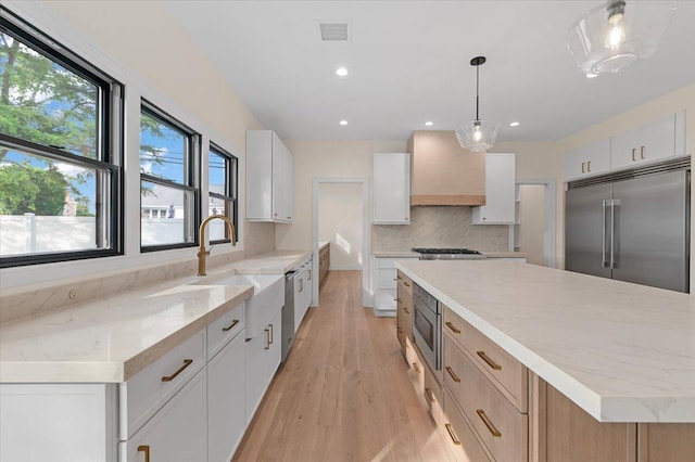 4 Haven Ln, Old Bethpage, NY 11804 - kitchen featuring built in appliances, light wood finished floors, backsplash, a spacious island, and light stone counters