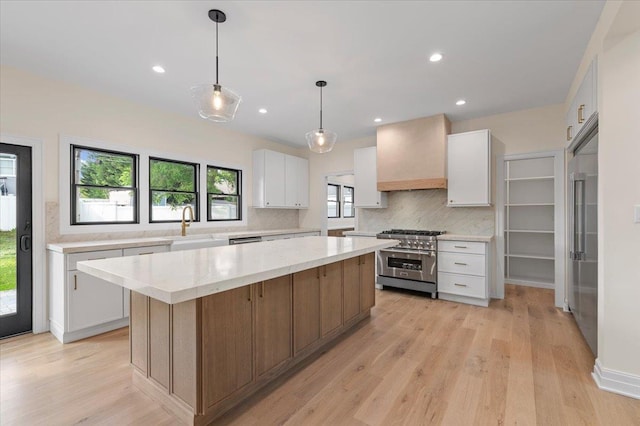 4 Haven Ln, Old Bethpage, NY 11804 - kitchen featuring high end appliances, custom range hood, tasteful backsplash, white cabinetry, and a center island