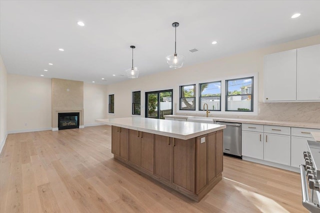 4 Haven Ln, Old Bethpage, NY 11804 - kitchen featuring stainless steel appliances, a center island, light countertops, white cabinetry, and light wood-style flooring