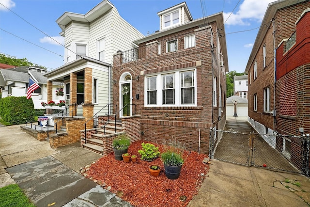 131 E 238th St, Bronx, NY 10470 - view of front of property with brick siding, a gate, an outdoor structure, a detached garage, and a balcony