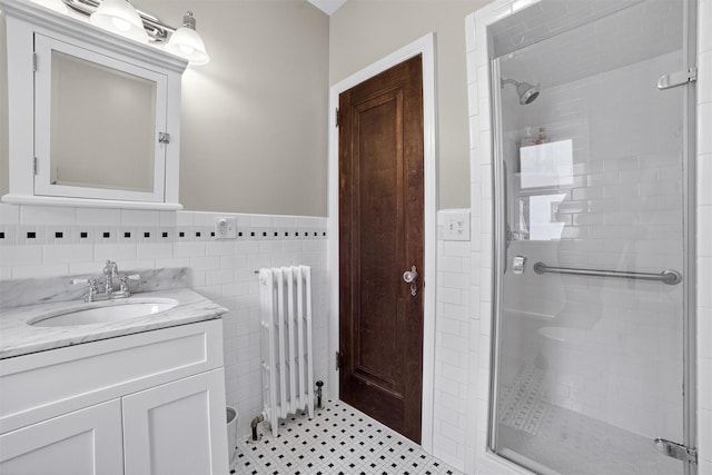 131 E 238th St, Bronx, NY 10470 - bathroom featuring radiator heating unit, a stall shower, vanity, a wainscoted wall, and tile walls