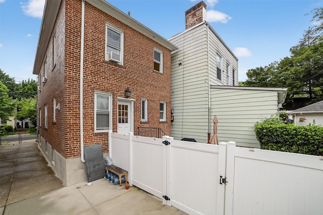 131 E 238th St, Bronx, NY 10470 - back of house with brick siding, a gate, cooling unit, and a chimney