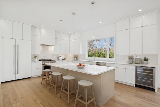 10 Broadwood Ct, Wainscott, NY 11975 - kitchen with wine cooler, high quality appliances, a breakfast bar area, light wood-type flooring, and a center island