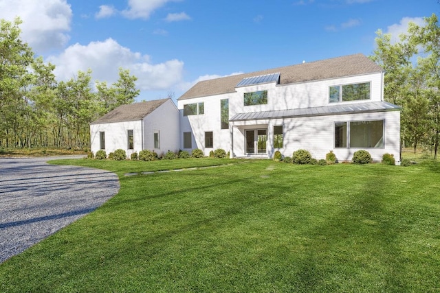 10 Broadwood Ct, Wainscott, NY 11975 - view of front of property with a front lawn, solar panels, a metal roof, and driveway